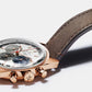 Luxury chronograph watch with a rose gold case, gray dial, and brown leather strap.