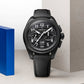 Black Zenith watch with chronograph features, displayed near blue and light gray geometric shapes.