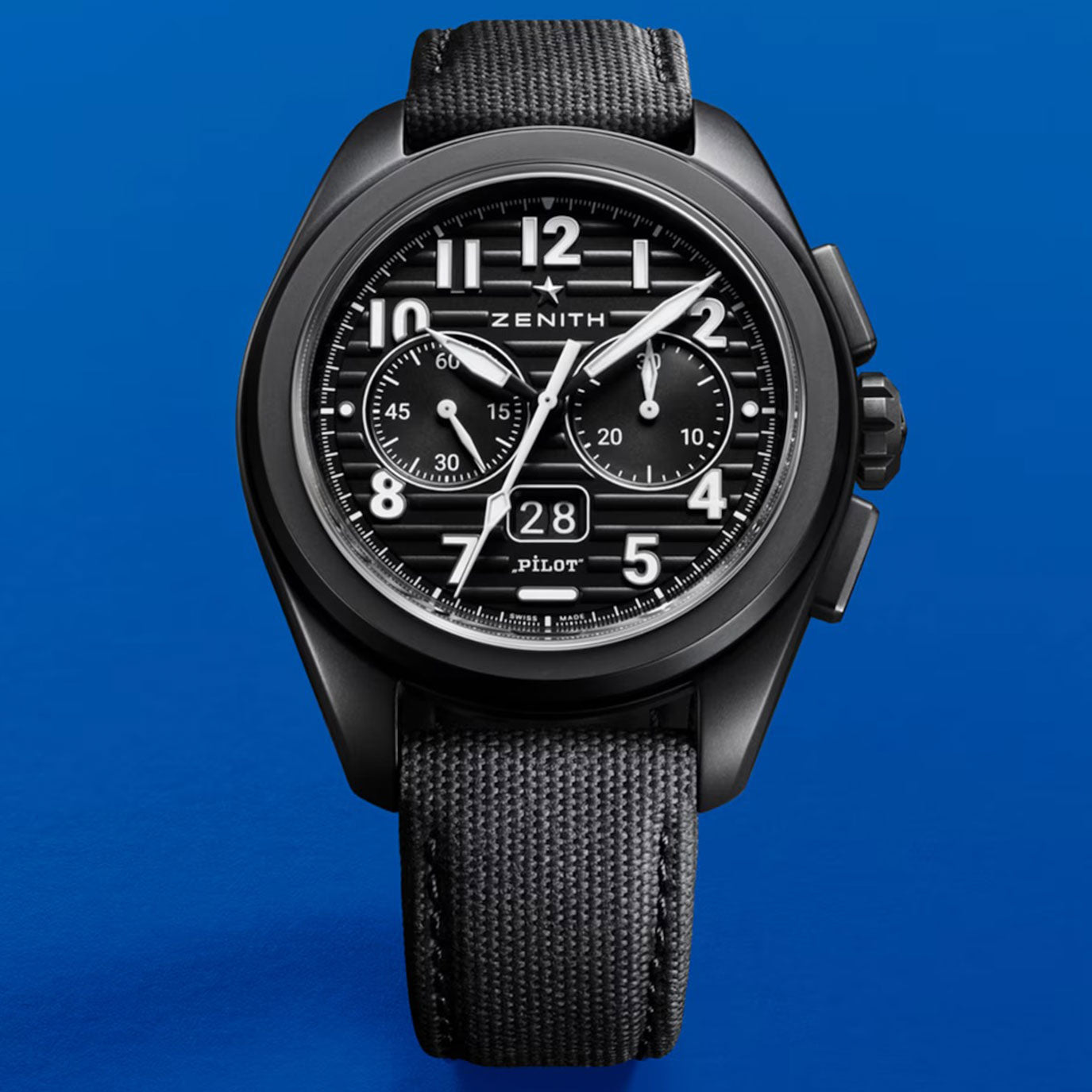 Black chronograph watch with a textured strap against a blue background.
