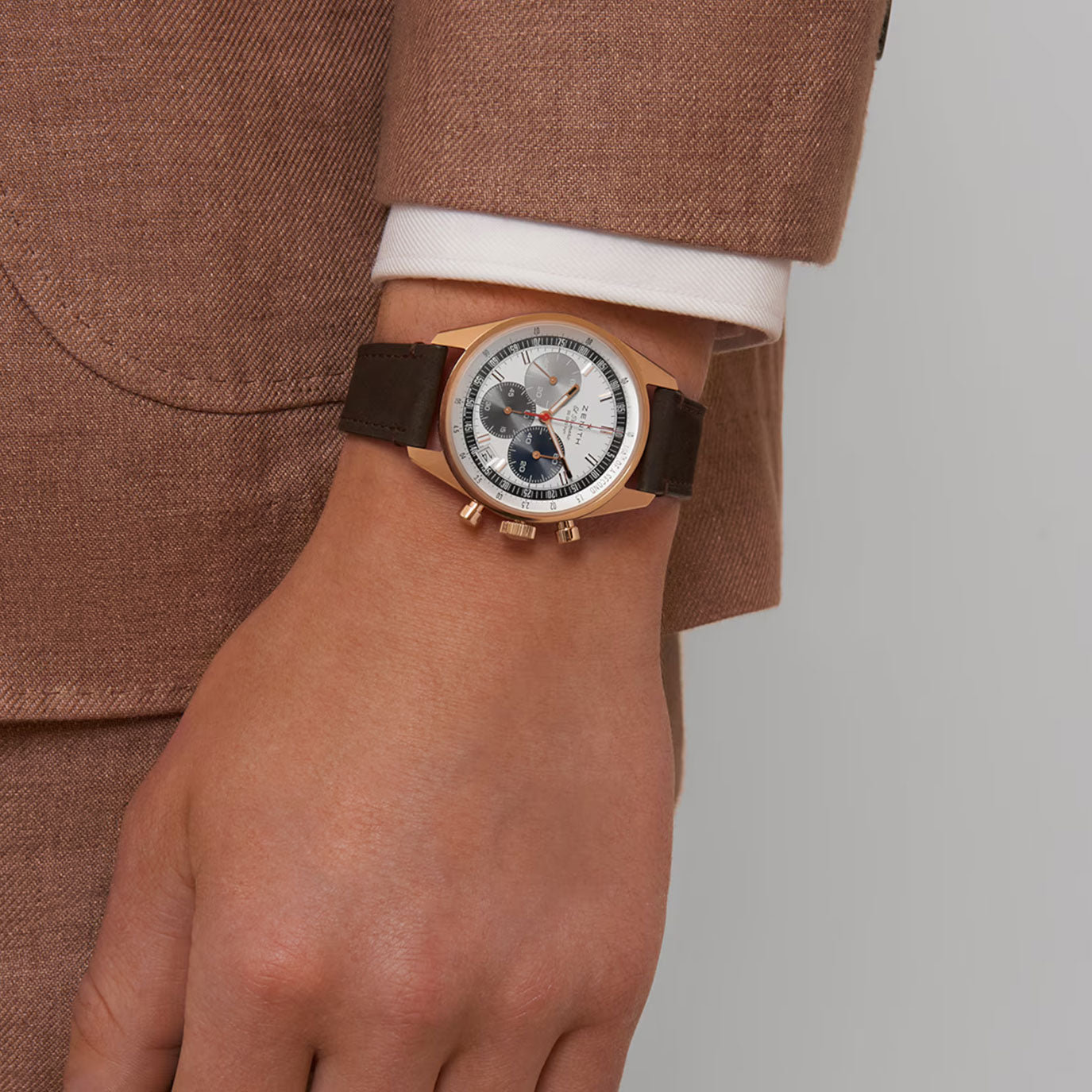 Brown leather strap watch on a wrist, featuring a white dial with black subdials and red accents.